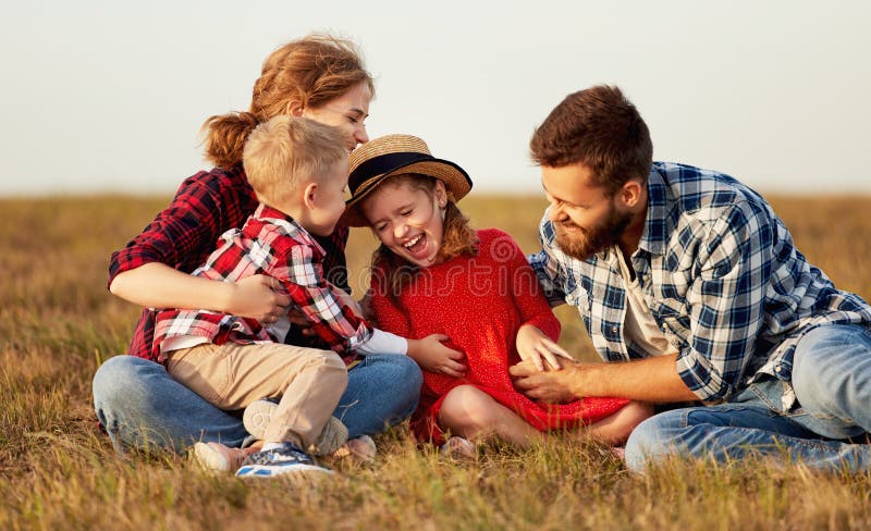 Happy family with kids sitting and laughing outdoors
