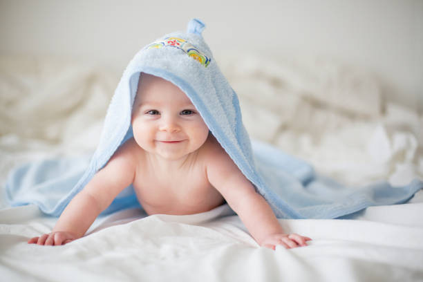 Newborn baby boy smiling under blue hooded towel